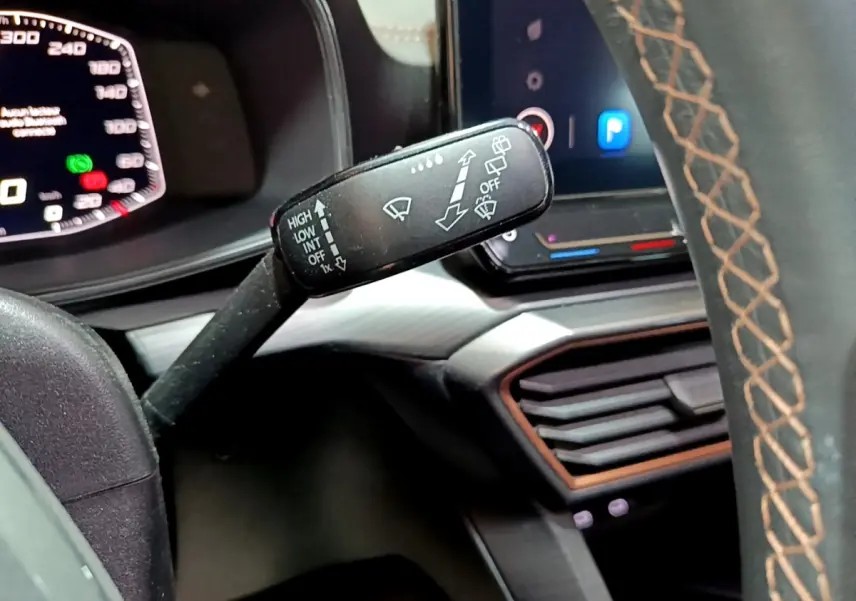 Gros plan sur la commande d’essuie-glace à gauche du volant cuir gris avec surpiqûres marron dans le CUPRA Formentor 2024.