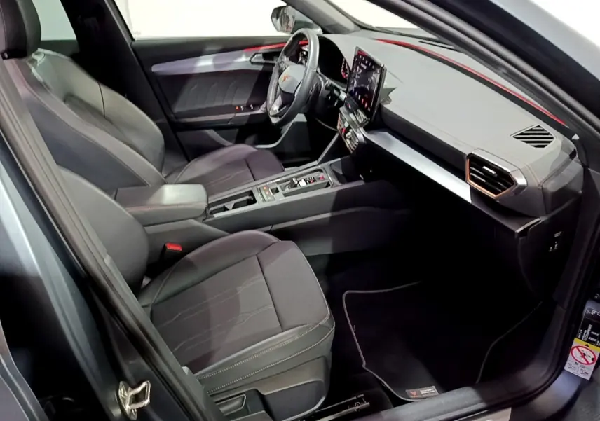 Vue intérieure côté conducteur de la CUPRA Formentor 1.5 TSI 2024, sièges noirs et tableau de bord moderne avec écran tactile.