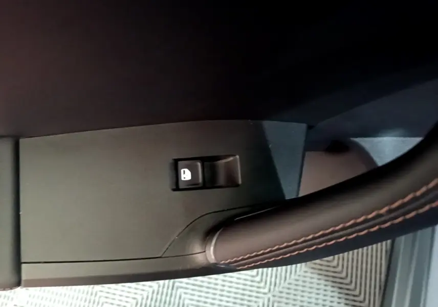 Gros plan sur le bouton de verrouillage des portes, avec poignée en cuir noir sur portière d'une CUPRA Formentor gris foncé.