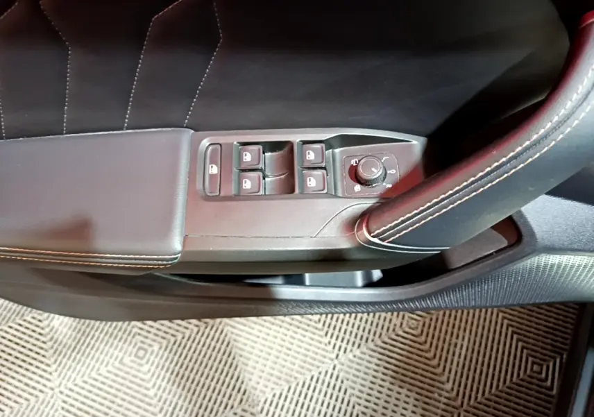 Gros plan sur la commande des vitres et rétroviseurs côté gauche en cuir noir avec surpiqûres blanches dans une CUPRA Formentor gris foncé.