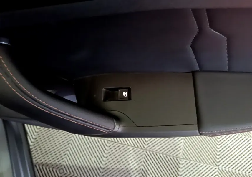 Détail de la portière côté gauche du CUPRA Formentor gris foncé avec bouton de verrouillage et surpiqûres orange.