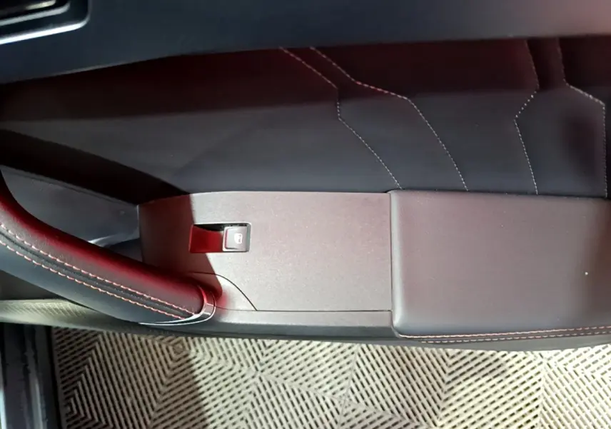 Détail de la porte intérieure côté gauche du CUPRA Formentor gris foncé avec surpiqûres rouges et bouton de verrouillage.