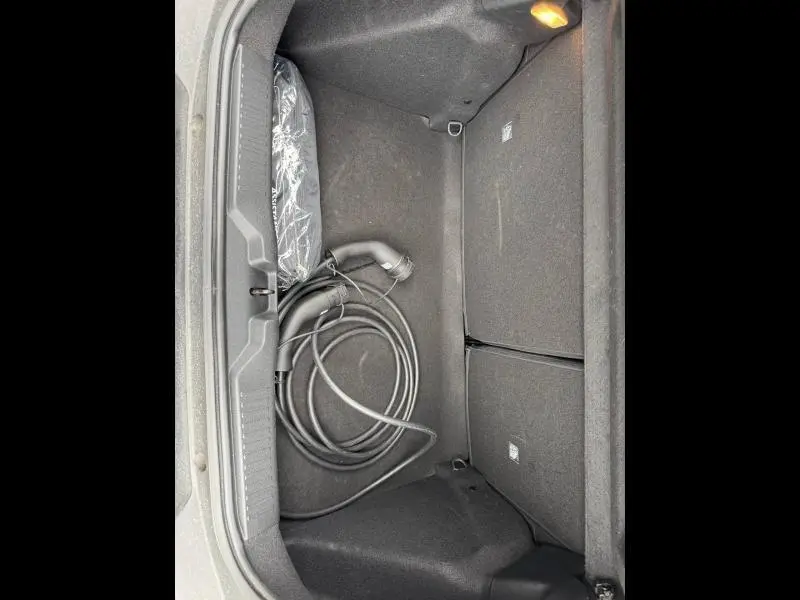 Coffre ouvert de la Citroën C3 électrique 2025 noir, vue plongeante montrant câble de recharge et éclairage intérieur.