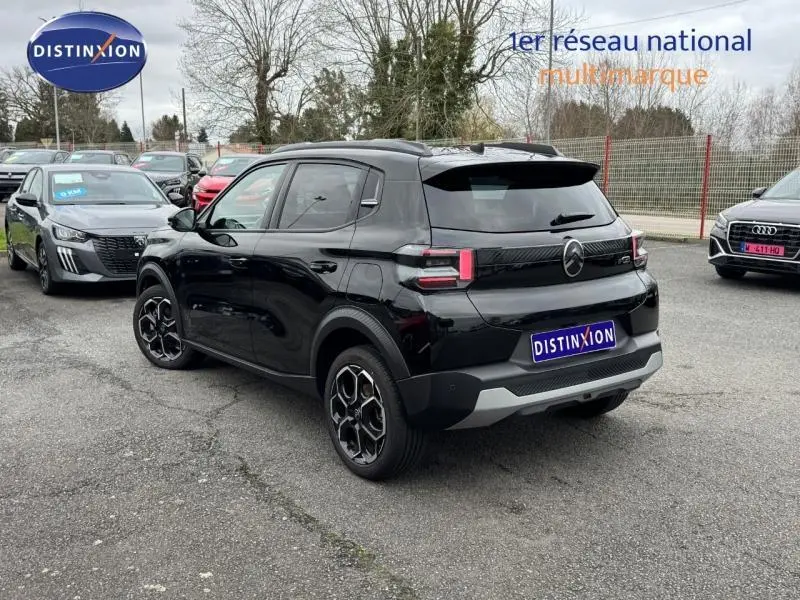 Vue 3/4 arrière d'une Citroën C3 électrique 2025 en noir Perla Nera avec jantes alu et feux arrière LED distinctifs.