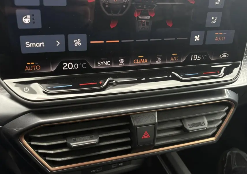 Gros plan sur la console centrale du Cupra Formentor blanc, montrant l'écran tactile et les commandes de climatisation.