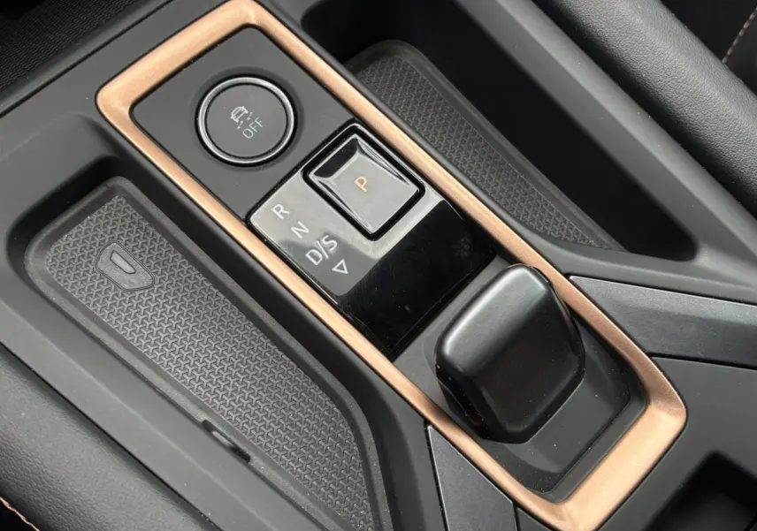 Gros plan sur la console centrale noire et cuivre du CUPRA Formentor avec sélecteur de boîte auto et bouton de contrôle.