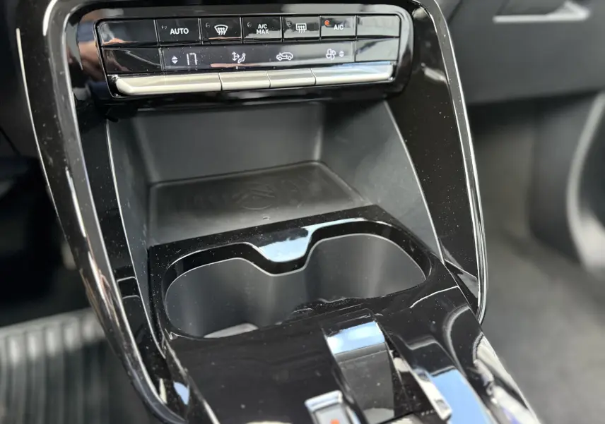 Gros plan sur la console centrale noire du Citroën C3 Aircross Hybrid 145, avec commandes climatisation et porte-gobelets.