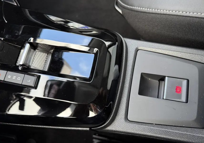 Gros plan sur la console centrale noire brillante de la Citroën C3 Aircross Hybrid 145, avec levier de vitesses automatique et frein à main électrique.
