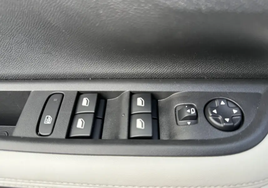 Gros plan sur les commandes de lève-vitres et réglage des rétroviseurs côté conducteur du Citroën C3 Aircross blanc banquise toit noir.