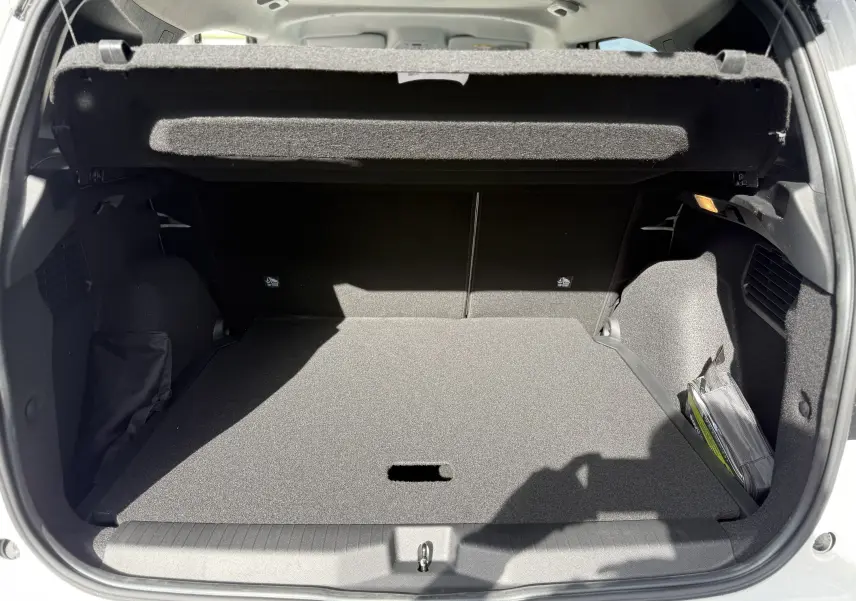 Vue arrière du coffre ouvert d'une Citroën C3 Aircross blanc banquise avec toit noir, montrant un espace de rangement vide et bien éclairé.