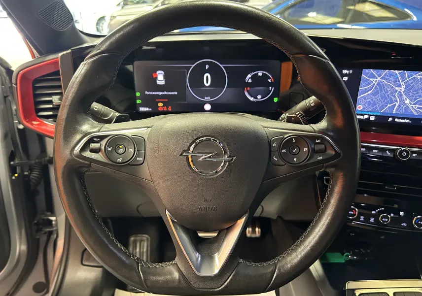 Vue centrée sur le volant noir de l'Opel Mokka GS Line 2022 avec tableau de bord numérique et écran GPS en arrière-plan.