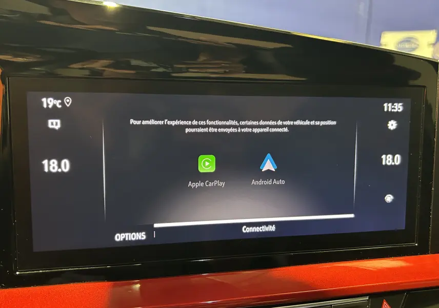 Écran tactile central de l’Opel Mokka GS Line 2022 affichant les options Apple CarPlay et Android Auto, avec tableau de bord rouge visible.