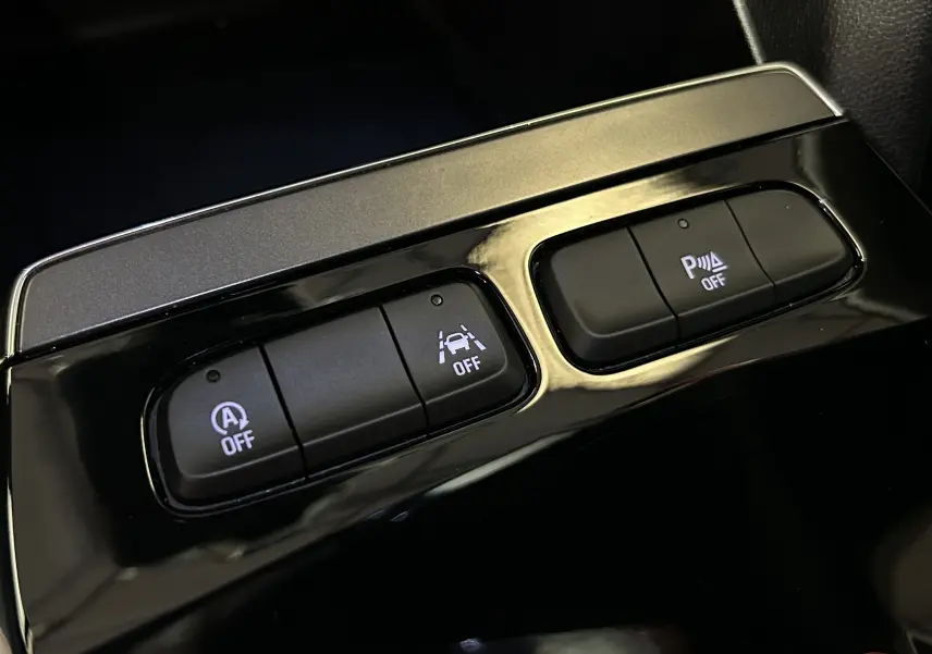 Gros plan sur les boutons de commande du système d'assistance dans l'habitacle noir brillant de l'Opel Mokka GS Line gris.