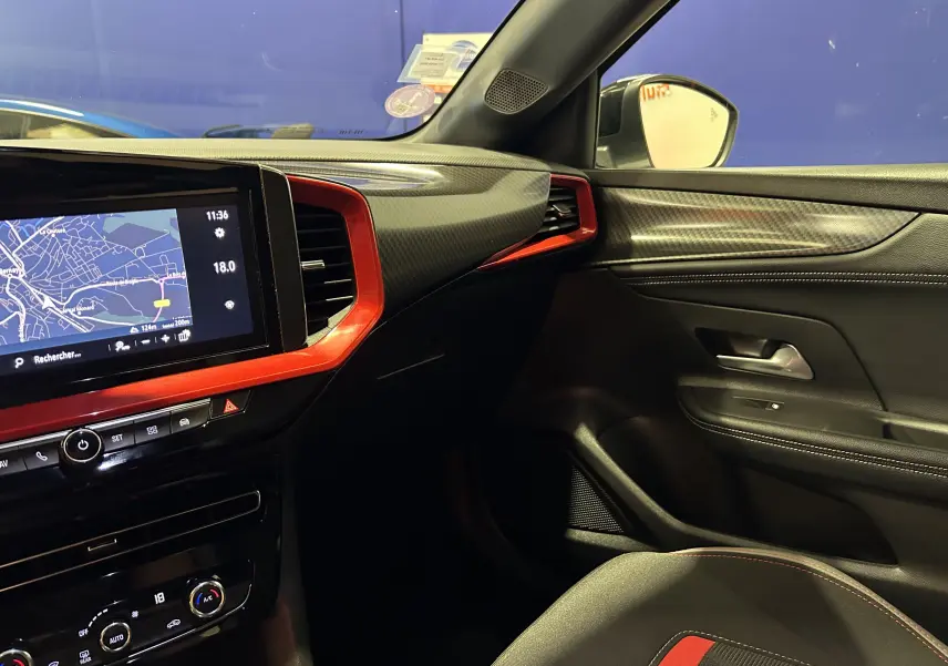 Vue intérieure côté passager de l'Opel Mokka GS Line 2022 avec tableau de bord noir et inserts rouges, écran tactile allumé.