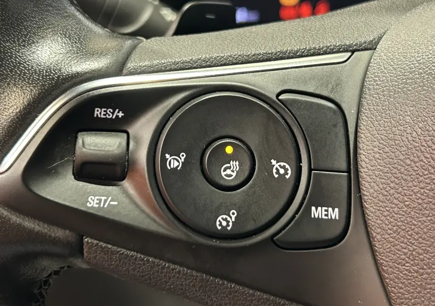 Gros plan sur les commandes du régulateur de vitesse au volant noir de l’Opel Mokka GS Line gris.
