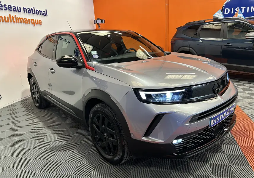 Vue 3/4 avant droite d’un Opel Mokka GS Line gris avec toit noir et jantes noires, en showroom intérieur.