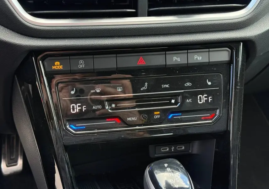 Vue rapprochée de la console centrale du Volkswagen T-Roc 2025, avec commandes climatisation et levier de boîte auto.