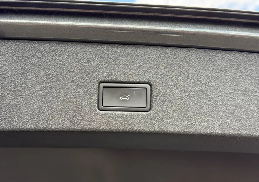 Bouton d'ouverture électrique du coffre sur la garniture intérieure d'un Volkswagen T-Roc gris Indium métallisé.