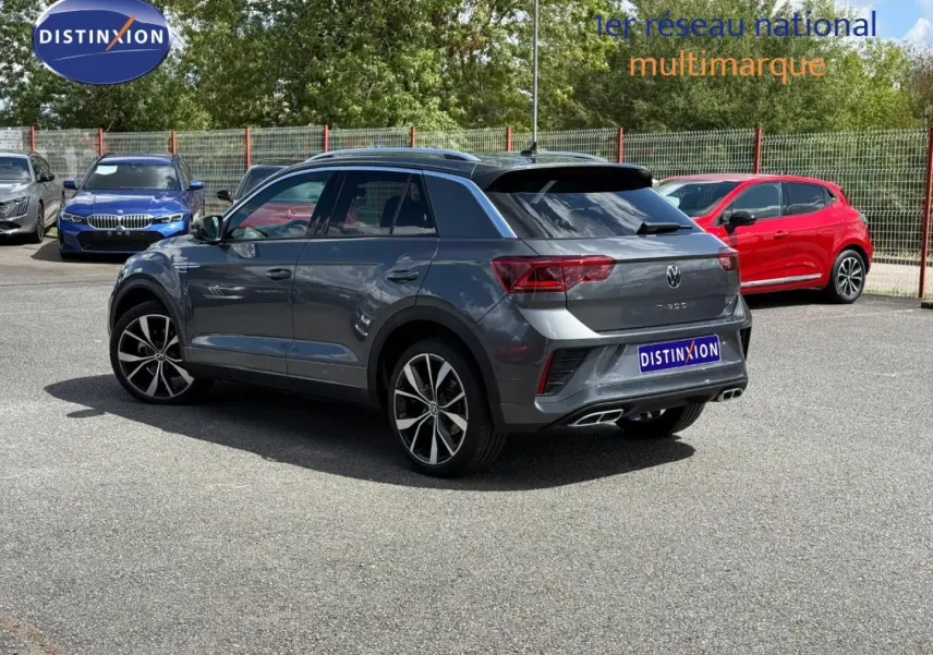 Volkswagen T-Roc gris Indium métallisé, vue 3/4 arrière droit, avec jantes alliage et sorties d’échappement chromées.