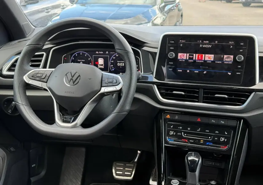 Vue intérieure du tableau de bord du Volkswagen T-Roc 2025 avec volant multifonction et écran tactile central.