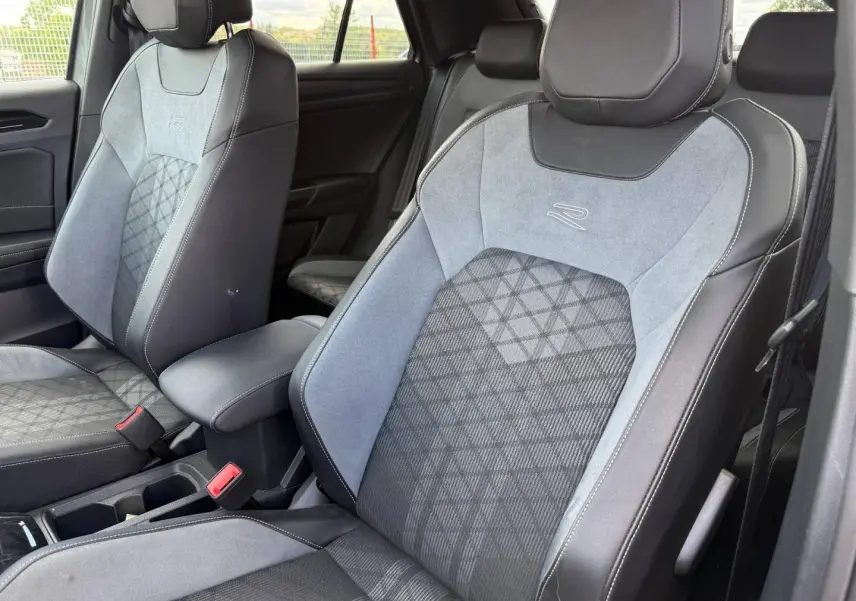 Vue rapprochée des sièges avant gris clair et noir en tissu et cuir avec logo R dans l’habitacle du Volkswagen T-Roc 2025.