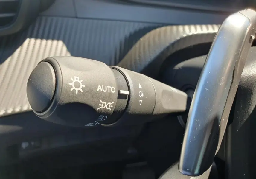 Gros plan sur la commande de phares automatique dans l'habitacle du Peugeot 208 gris Sellenium 2025.