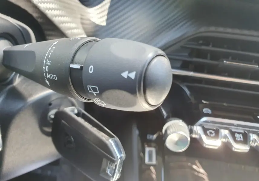 Gros plan sur la commande d’essuie-glace à gauche du volant dans l’habitacle du Peugeot 208 gris Sellenium.