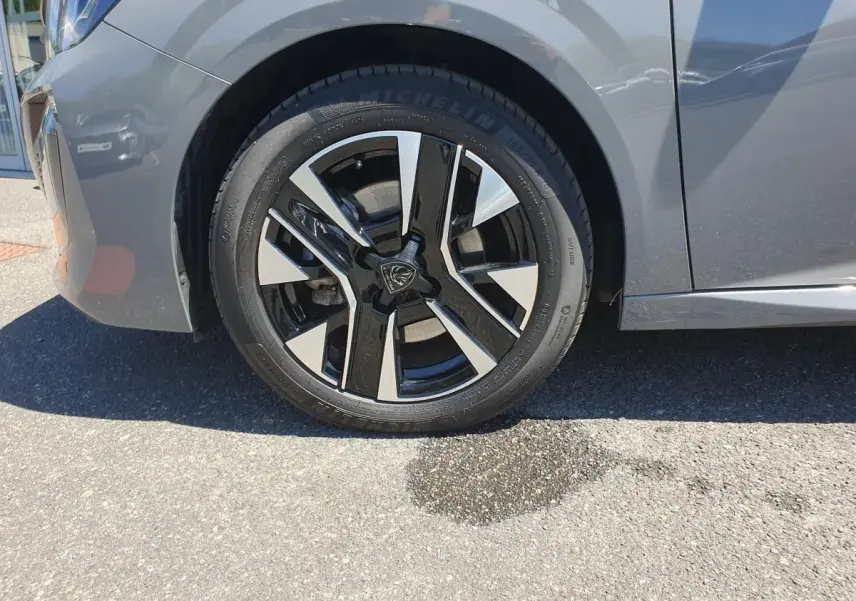 Gros plan sur la roue avant gauche de la Peugeot 208 gris Sélénnium avec jante alliage diamantée bi-tons.