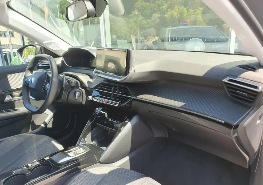 Vue intérieure côté conducteur du Peugeot 208 gris Sellenium, avec tableau de bord moderne et écran tactile central.