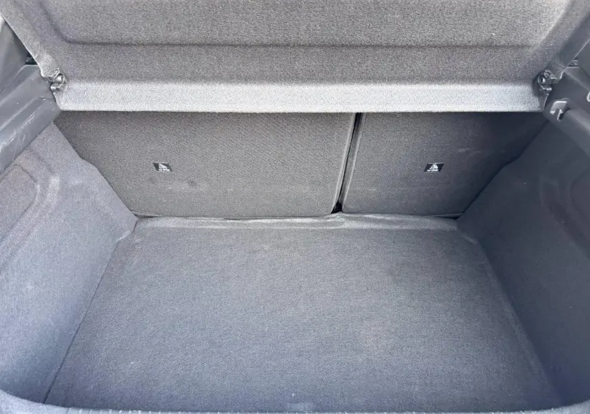 Coffre ouvert de Peugeot 208 1.2 100ch Allure, vue intérieure montrant la moquette grise et la banquette arrière rabattable.