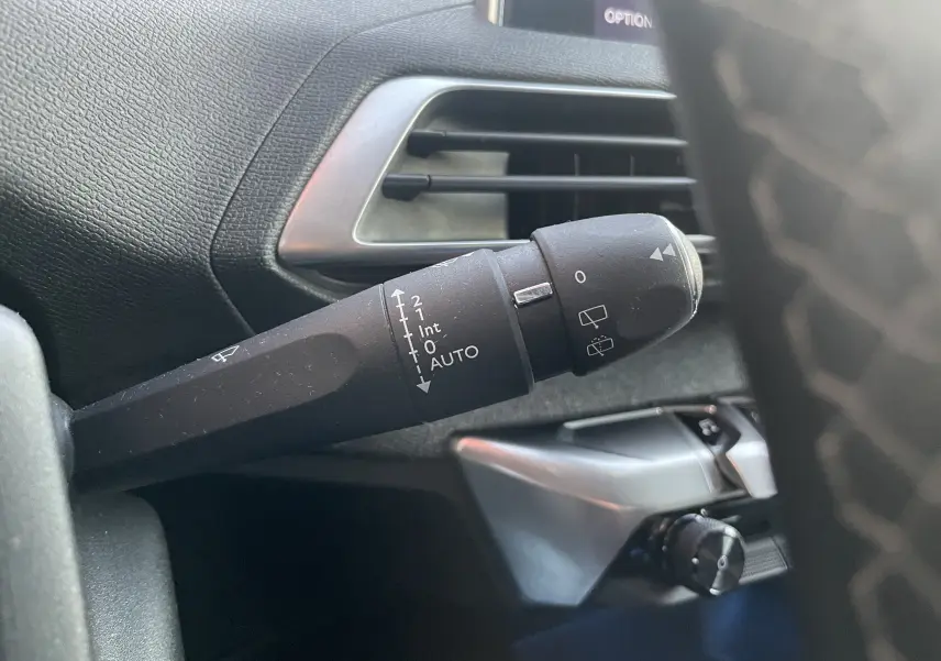 Gros plan sur la commande des essuie-glaces du Peugeot 3008 blanc nacré, avec tableau de bord noir en arrière-plan.