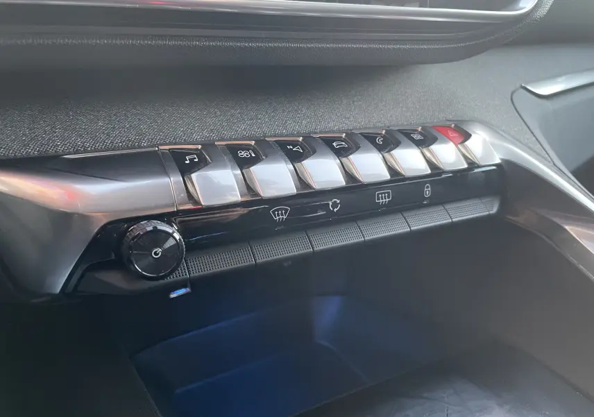 Gros plan sur la console centrale du Peugeot 3008 blanc nacré, montrant les boutons de commande et la molette de réglage.