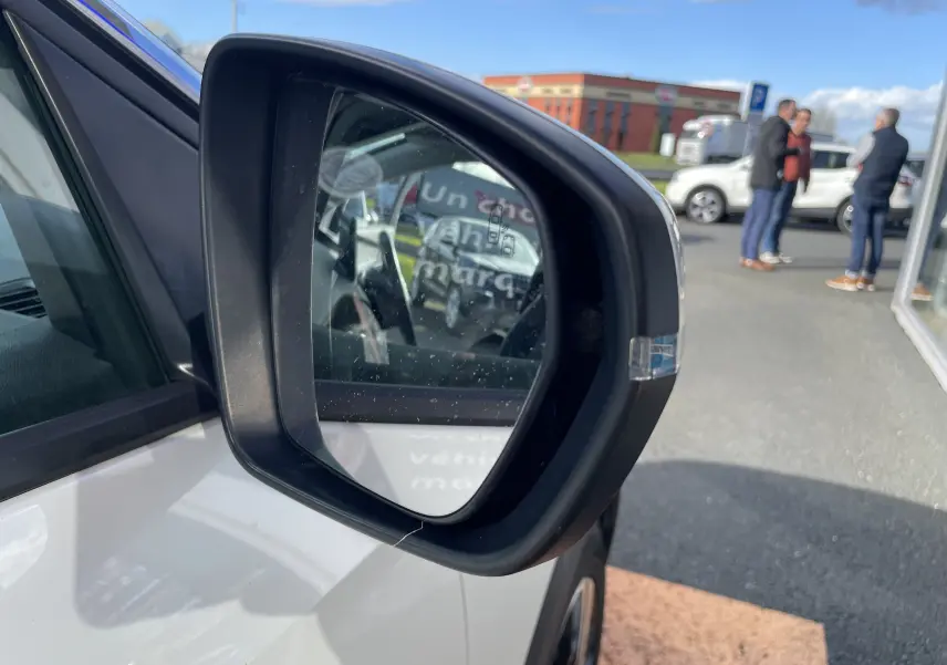 Rétroviseur côté gauche d’un Peugeot 3008 blanc nacré, avec reflet partiel de l’habitacle et arrière-plan extérieur.