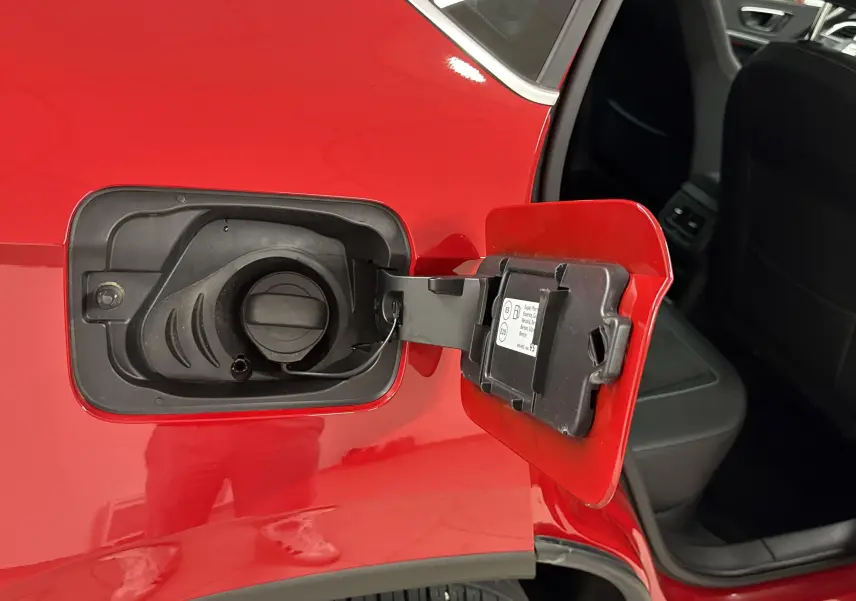 Gros plan sur la trappe de carburant ouverte côté gauche d'un SEAT Ateca Rouge Velvet avec porte arrière ouverte.