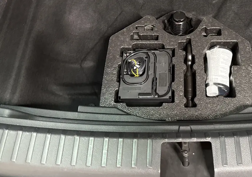 Gros plan sur le plancher de coffre à double fond du SEAT Ateca 2024, montrant les outils de bord rangés.