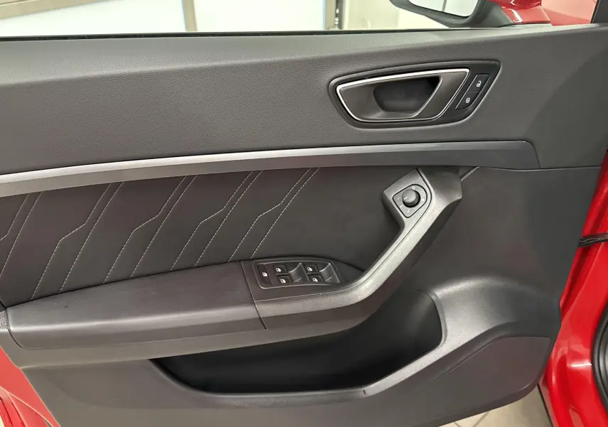 Gros plan sur la porte avant gauche rouge velvet du SEAT Ateca 2024 avec commandes de vitres et poignée intégrée.
