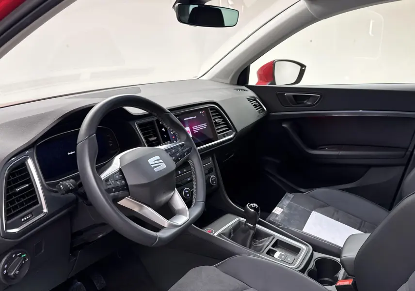 Intérieur avant droit du SEAT Ateca rouge velvet 2024, volant multifonction et levier de vitesse manuel visibles.