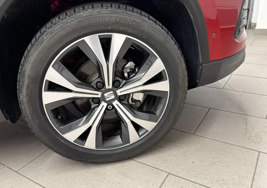 Gros plan sur la roue avant droite du SEAT Ateca rouge velvet, mettant en valeur la jante alliage moderne.