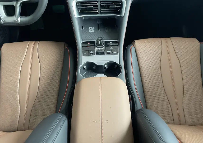 Vue plongeante sur la console centrale et les sièges avant en similicuir vegan marron et noir avec surpiqûres orange du BYD SEAL U.