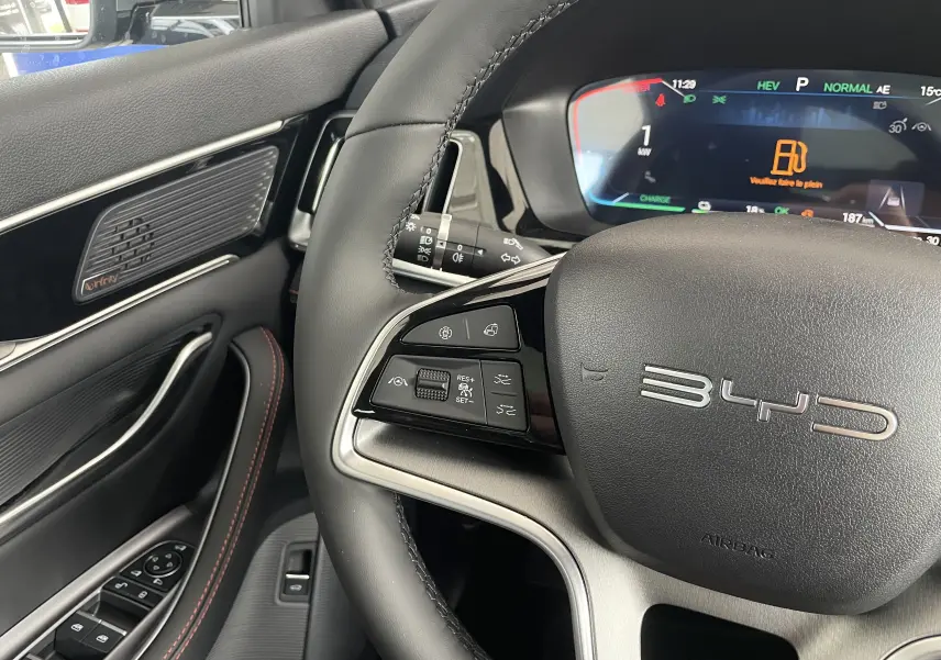 Vue rapprochée du volant noir et du tableau de bord numérique du BYD SEAL U 2026 avec commandes multifonctions et haut-parleur Infinity.