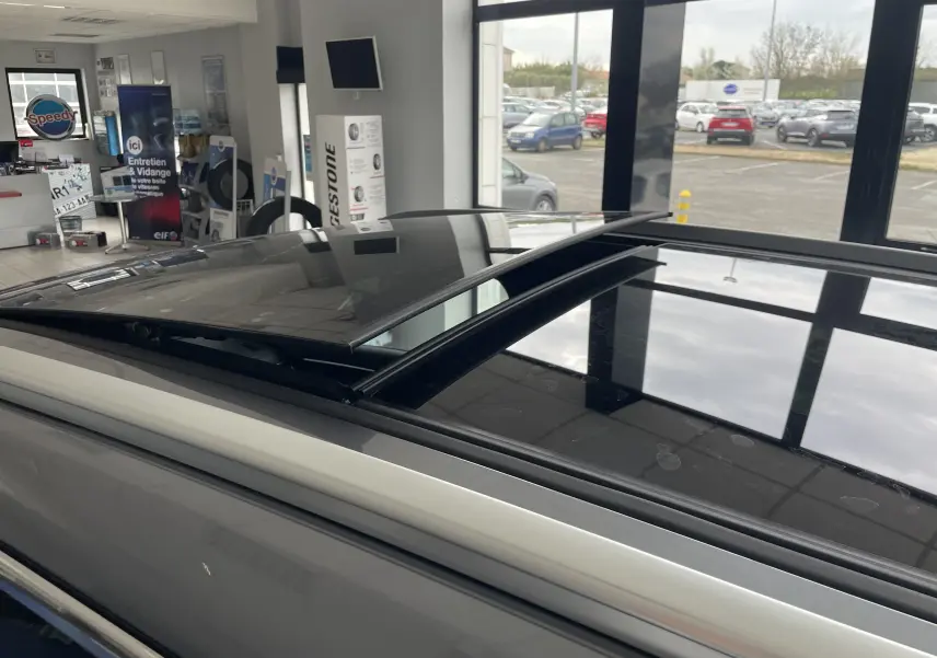 Vue rapprochée du toit ouvrant panoramique ouvert sur le côté gauche d’un BYD SEAL U gris TIME GREY en showroom.