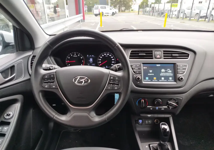 Vue intérieure centrée sur le volant et le tableau de bord de la Hyundai i20 2018, avec écran tactile et commandes au volant.