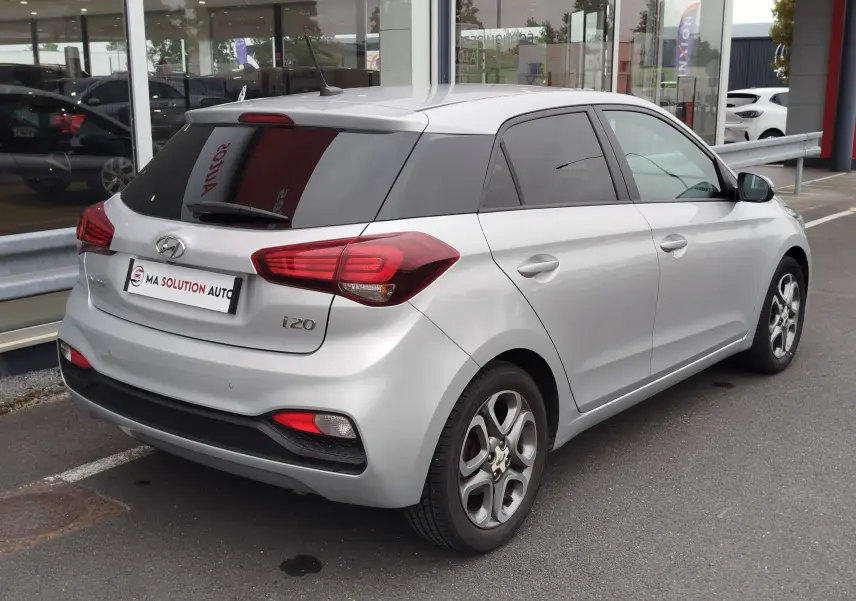 Vue 3/4 arrière droite d'une Hyundai i20 2018 gris argenté avec vitres teintées et jantes alliage.