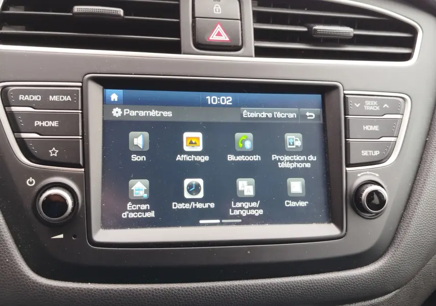 Écran tactile central de la Hyundai i20 2018 affichant le menu paramètres avec commandes autour en plastique noir.