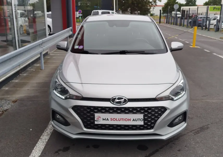 Vue avant d'une Hyundai i20 2018 couleur Sleek Silver Métal avec calandre noire et feux LED allumés.