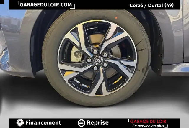 Gros plan sur la roue avant droite d'une Toyota Yaris hybride gris foncé, avec jante alliage au design moderne.