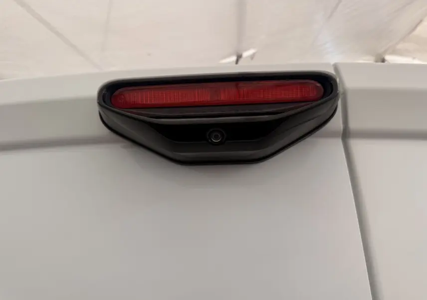Gros plan sur le feu stop arrière rouge et la caméra de recul intégrée sur la porte blanche d'un Citroën Berlingo 2022.
