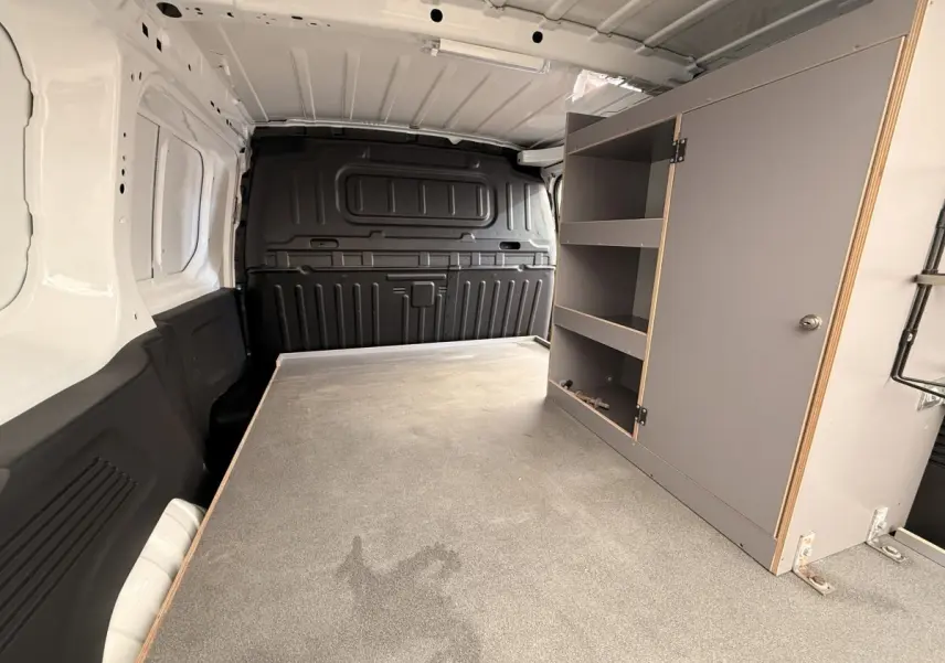 Vue intérieure arrière du Citroën Berlingo blanc avec cloison pleine et aménagement de rangement gris à droite.