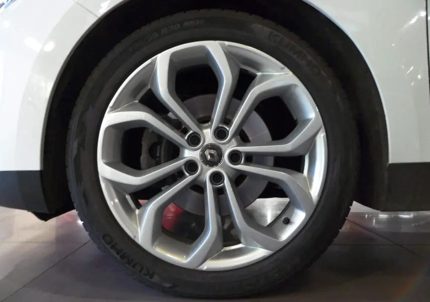 Gros plan sur la roue avant gauche blanche glacée du Renault Grand Scenic IV Blue dCi 120 CH BUSINESS avec jante alu.