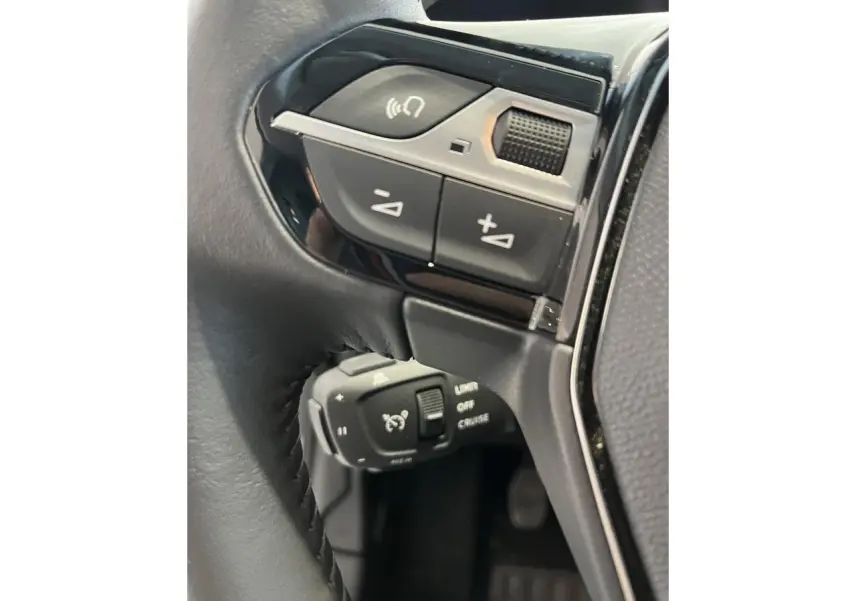 Gros plan sur commandes de régulateur de vitesse et volume au volant cuir noir de la Peugeot 208 gris clair Selenium